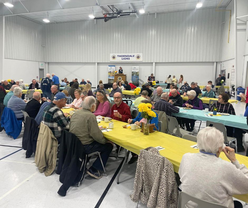 crowd of people sitting eating at the volunteer breakfast