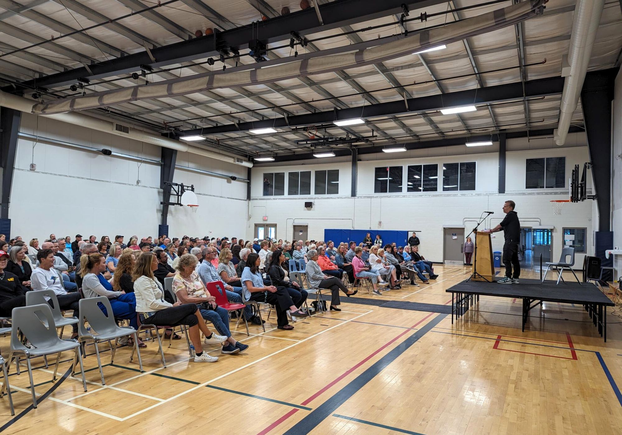 michael landsberg speaking in a gym to a crowd of people